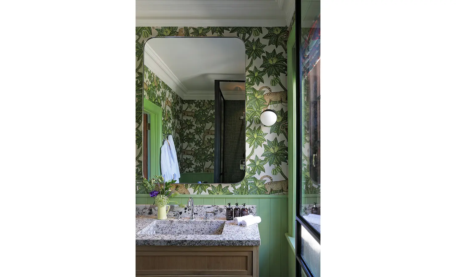 Perfect Hideaways — A lively bathroom with jungle-inspired wallpaper featuring leopards and lush green foliage. The marble countertop and modern fixtures contrast with the botanical whimsy. Bishopscourt, Bishops Hall.