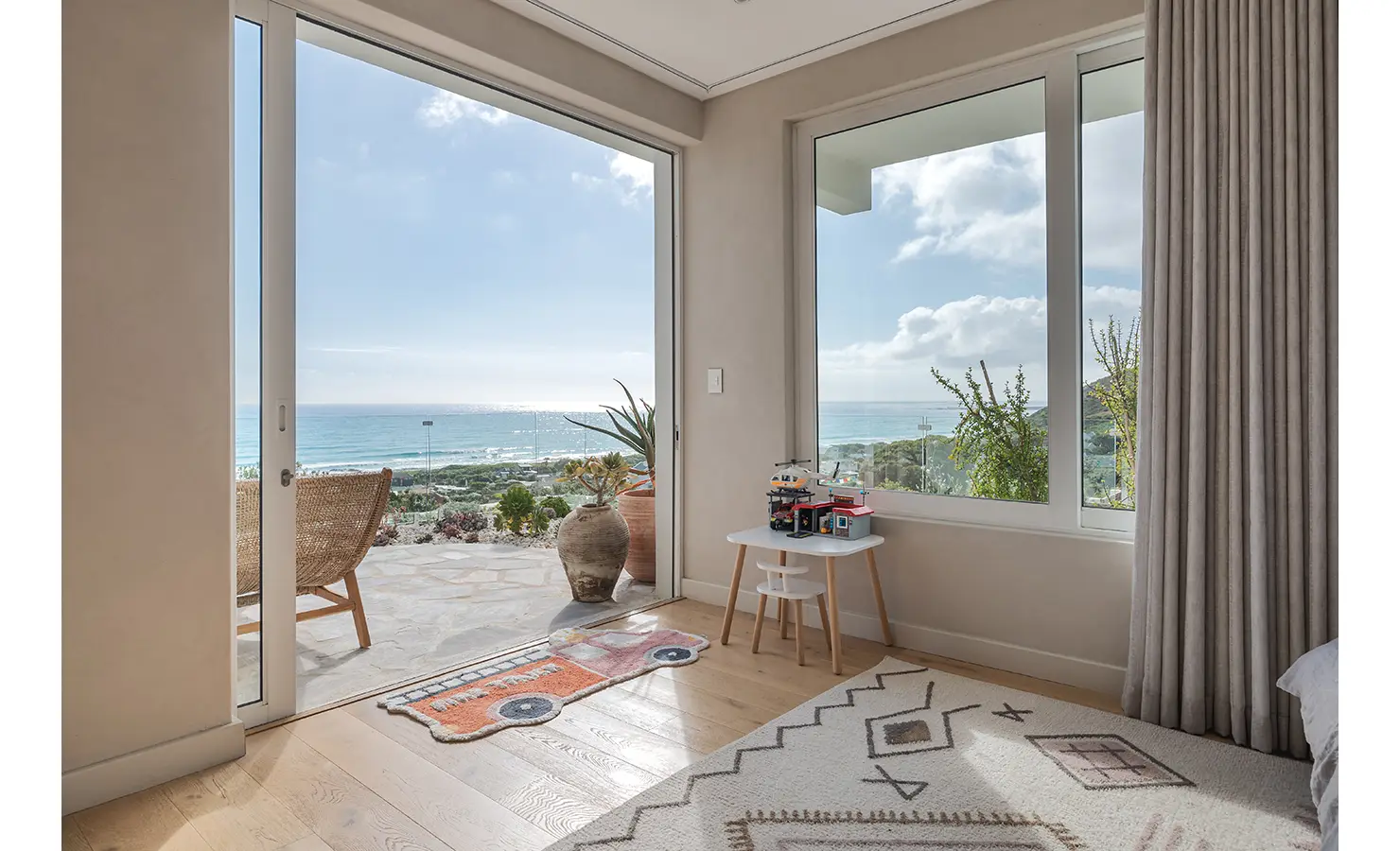 Perfect Hideaways: A breathtaking ocean-view bedroom with floor-to-ceiling glass doors opening to a private terrace. Natural light floods the space, highlighting the soft neutral decor and coastal-inspired details. Seaside Sanctuary, Scarborough.