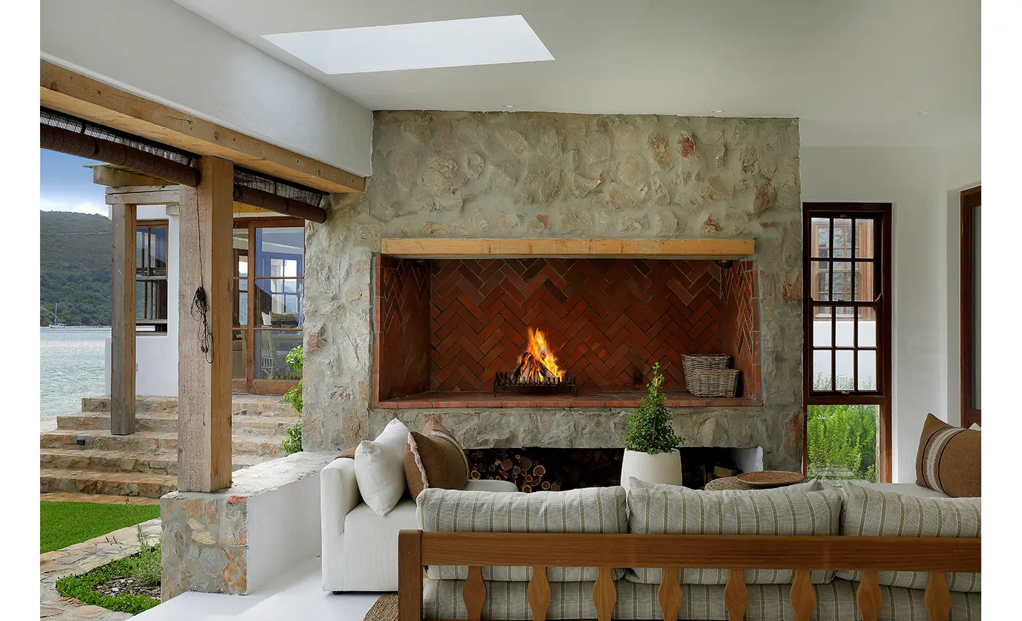 Perfect Hideaways: Cosy lounge with a large herringbone-brick hearth set in stone and views to the water, Knysna, Tides Reach