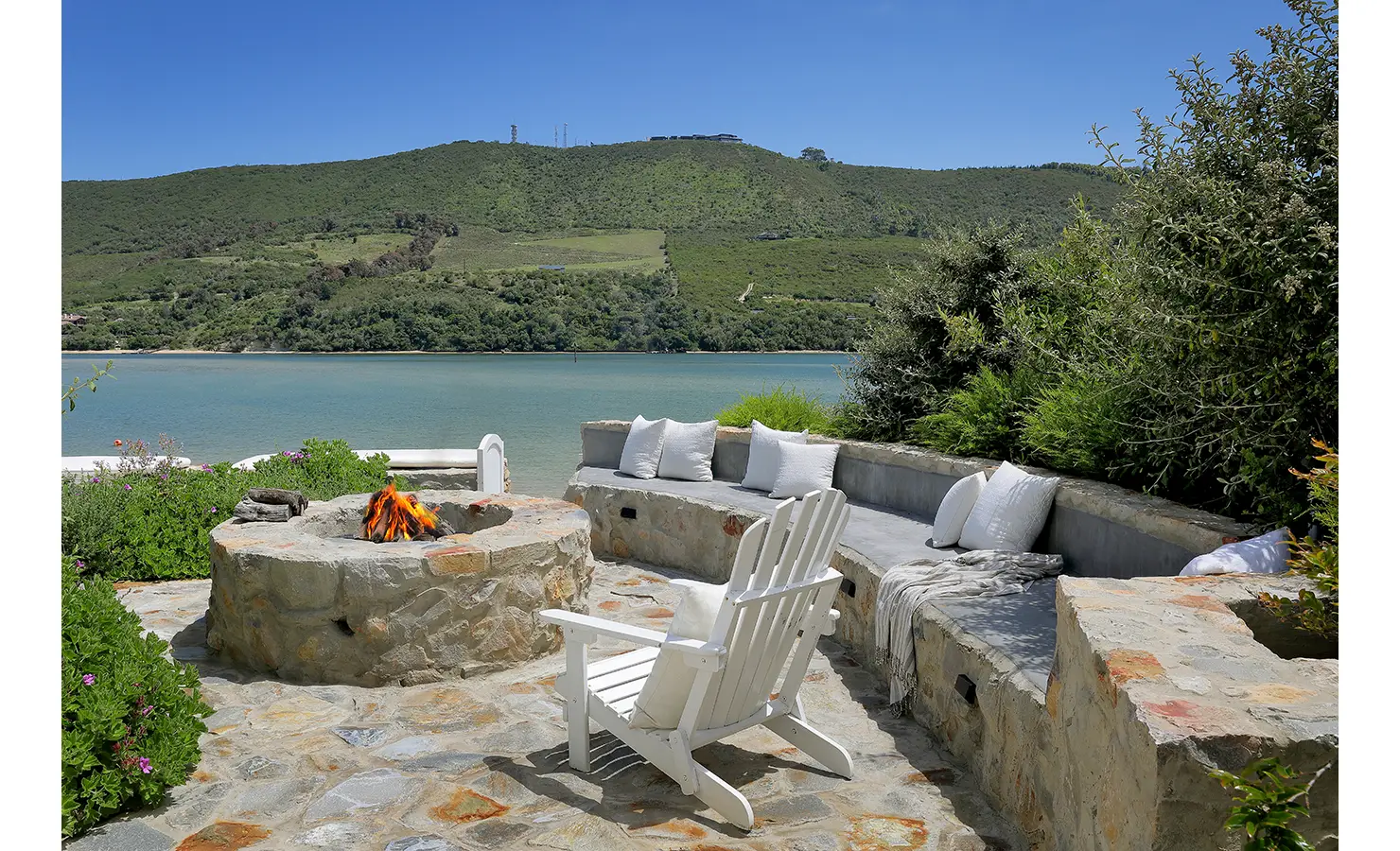 Perfect Hideaways: Lagoon-side firepit terrace with a curved built-in bench and Adirondack chairs for sunset gatherings, Knysna, Tides Reach