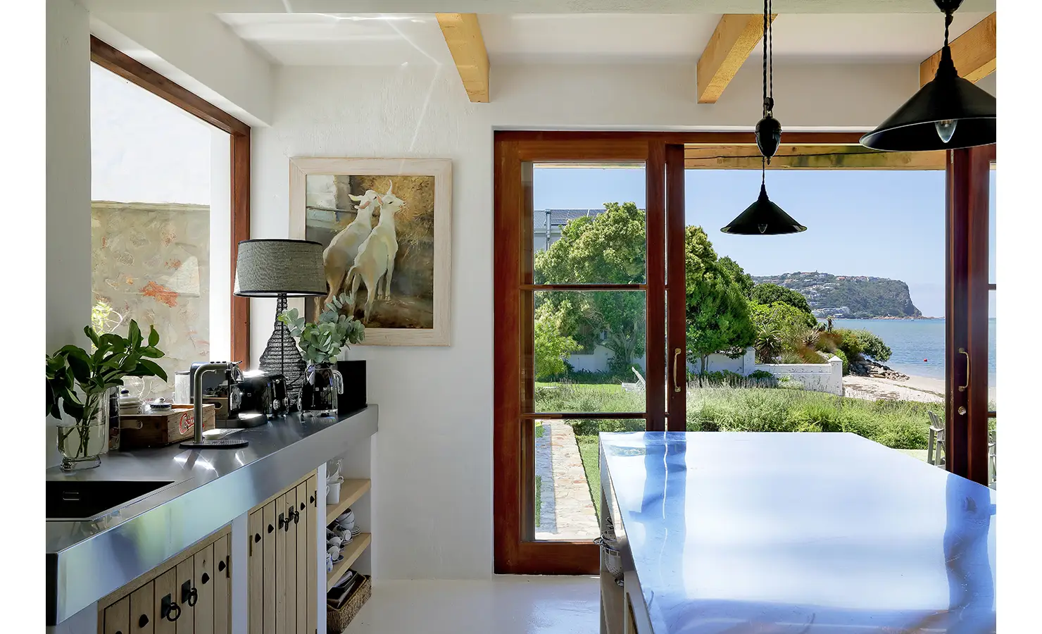 Perfect Hideaways: Coffee station and glossy island beneath black pendants, doors opening to garden, dunes and the Knysna Heads, Knysna, Tides Reach