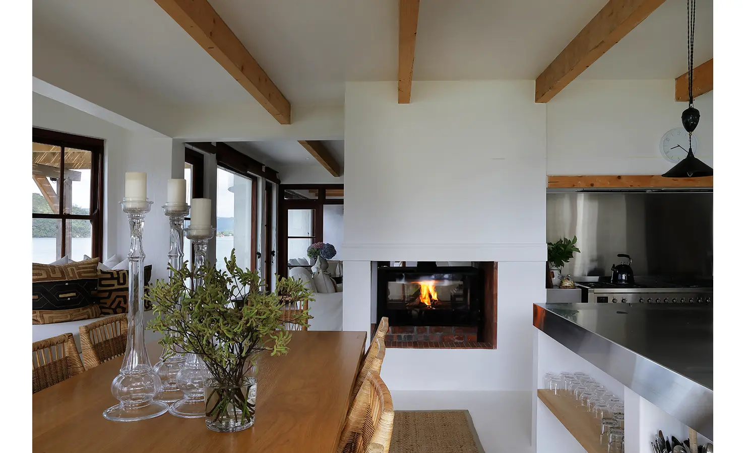 Perfect Hideaways: Dining table with tall glass candlesticks beside a double-sided hearth linking to the lounge, Knysna, Tides Reach