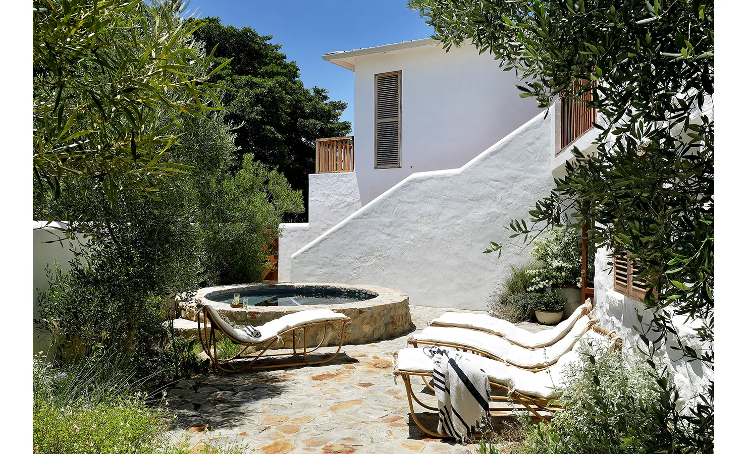 Perfect Hideaways: Secluded courtyard with a circular stone plunge pool, curved loungers and olive‑framed planting, Knysna, Tides Reach