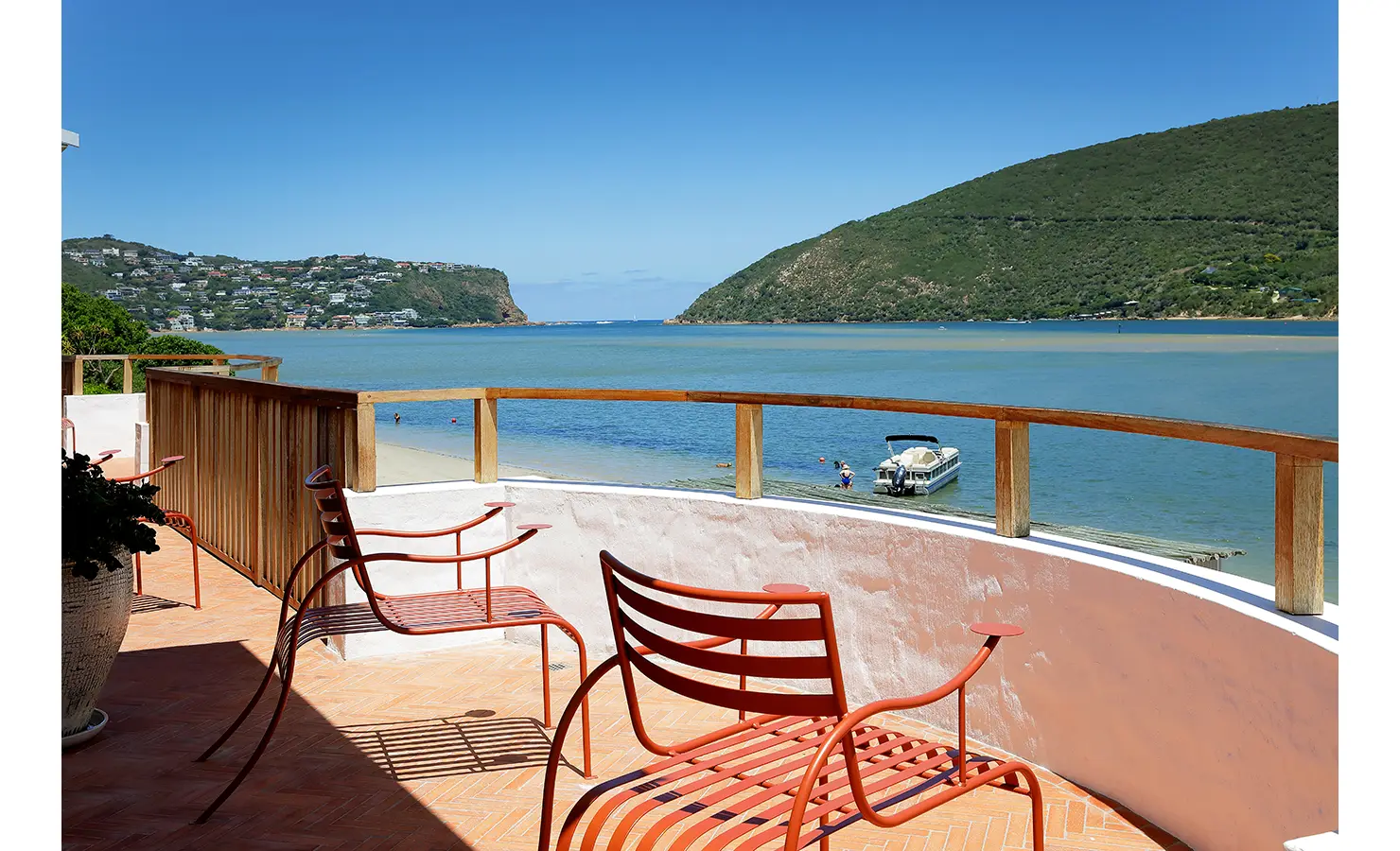 erfect Hideaways: Curved balcony with terracotta tiles and red metal chairs overlooking the lagoon and the Knysna Heads, Knysna, Tides Reach