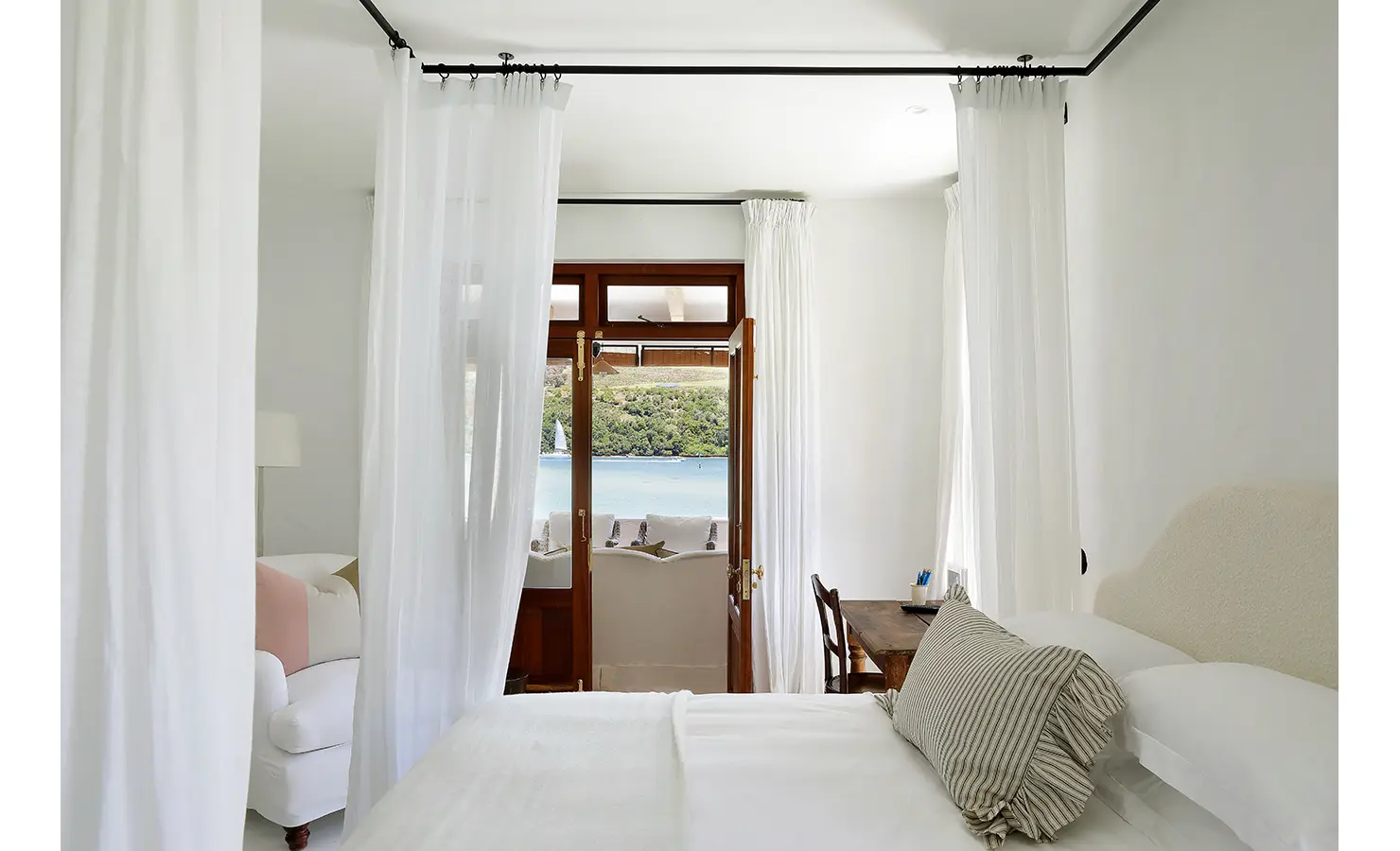 Perfect Hideaways: Canopy-draped bedroom opening to a small balcony with lagoon views, desk nook and soft white seating, Knysna, Tides Reach