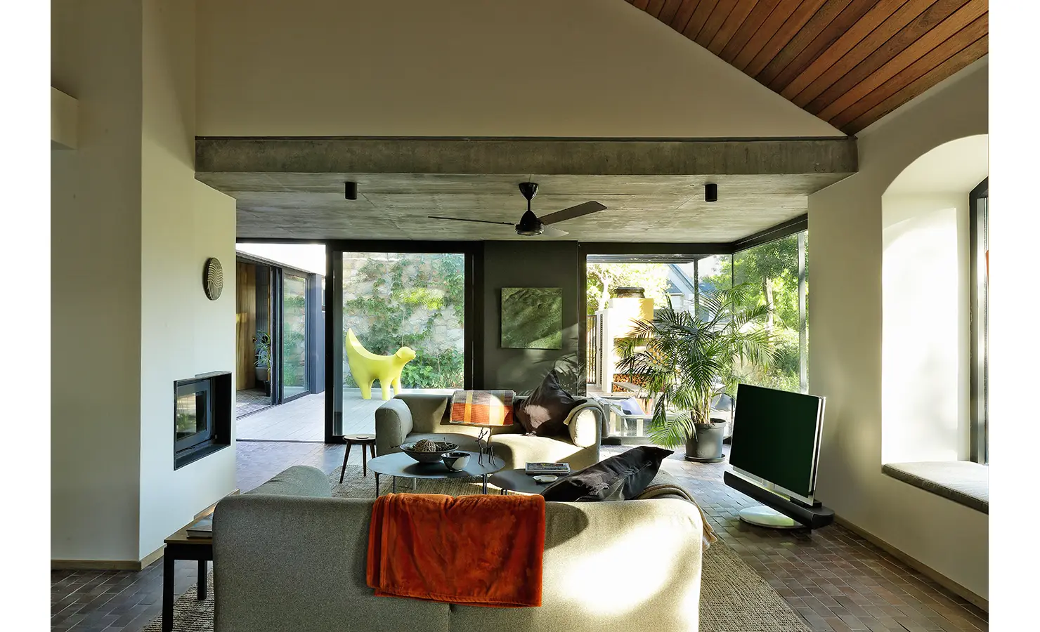 Perfect Hideaways: light-filled lounge with concrete soffit, ceiling fan, indoor greenery and playful yellow sculptural piece by the terrace, Franschhoek, The Garden House