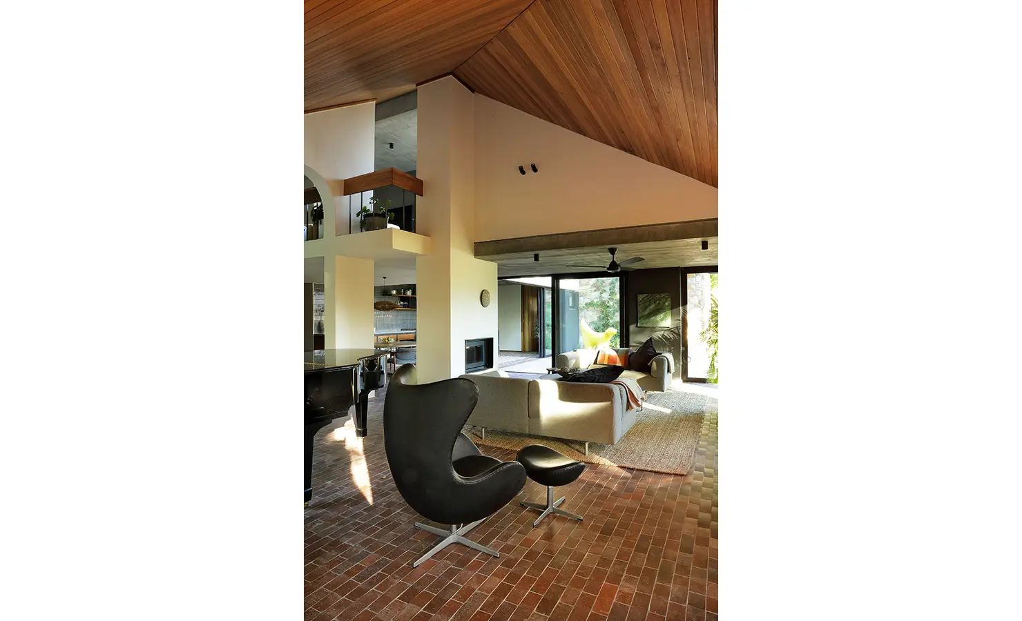 erfect Hideaways: open-plan living area with sculptural black lounge chair, grand piano, brick floors and warm timber ceiling, Franschhoek, The Garden House