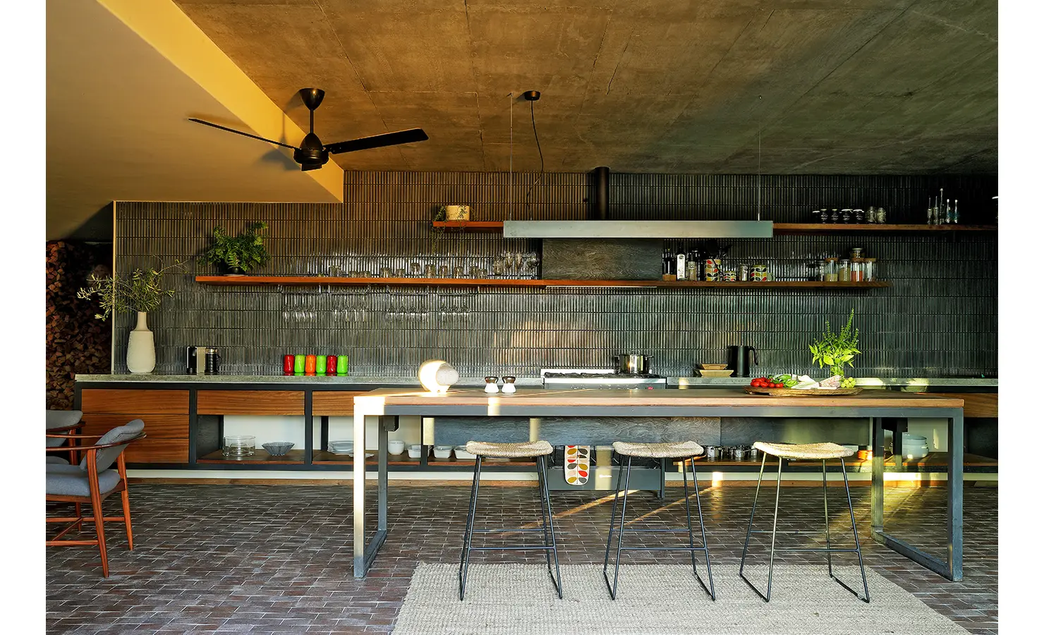 Perfect Hideaways: sleek open kitchen with long island, ribbed dark-tile splashback, open shelves and concrete ceiling, Franschhoek, The Garden House