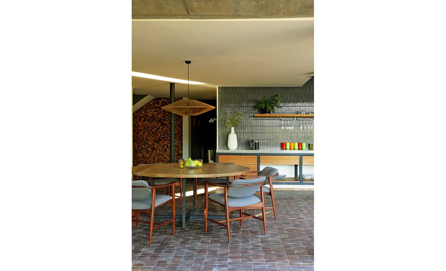Perfect Hideaways: intimate dining space with round wooden table, mid-century chairs, woven pendant and stacked firewood feature, Franschhoek, The Garden House
