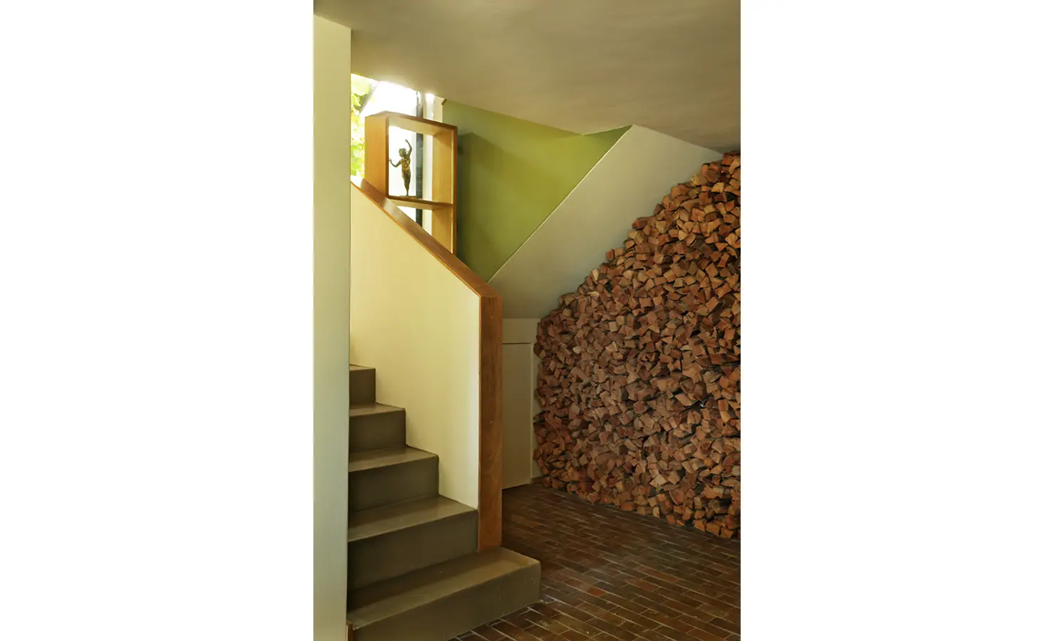 Perfect Hideaways: sculptural staircase with timber handrail beside a stacked firewood feature wall and sunlit niche, Franschhoek, The Garden House