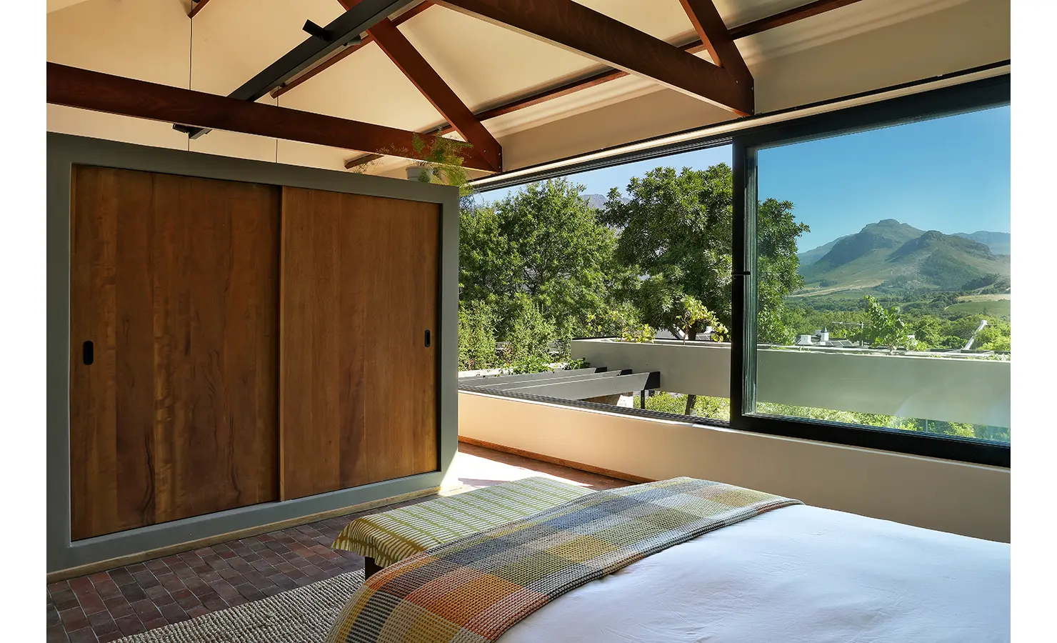 Perfect Hideaways: tranquil bedroom with sliding timber wardrobes and a picture window to vineyard and mountain vistas, Franschhoek, The Garden House
