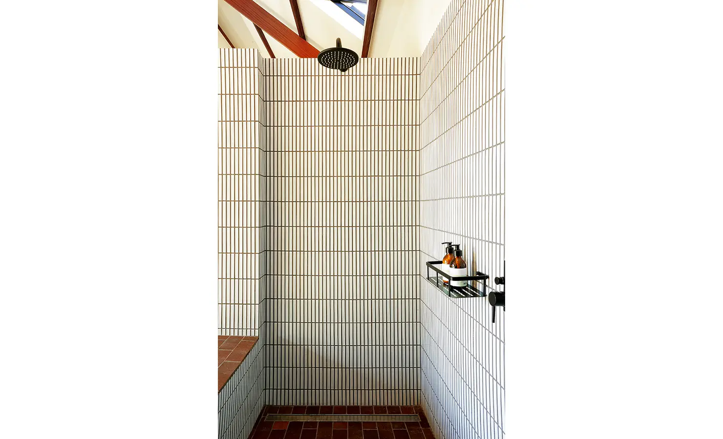 Perfect Hideaways: walk-in shower lined with slender white vertical tiles, rainfall head and black fittings over terracotta brick, Franschhoek, The Garden House