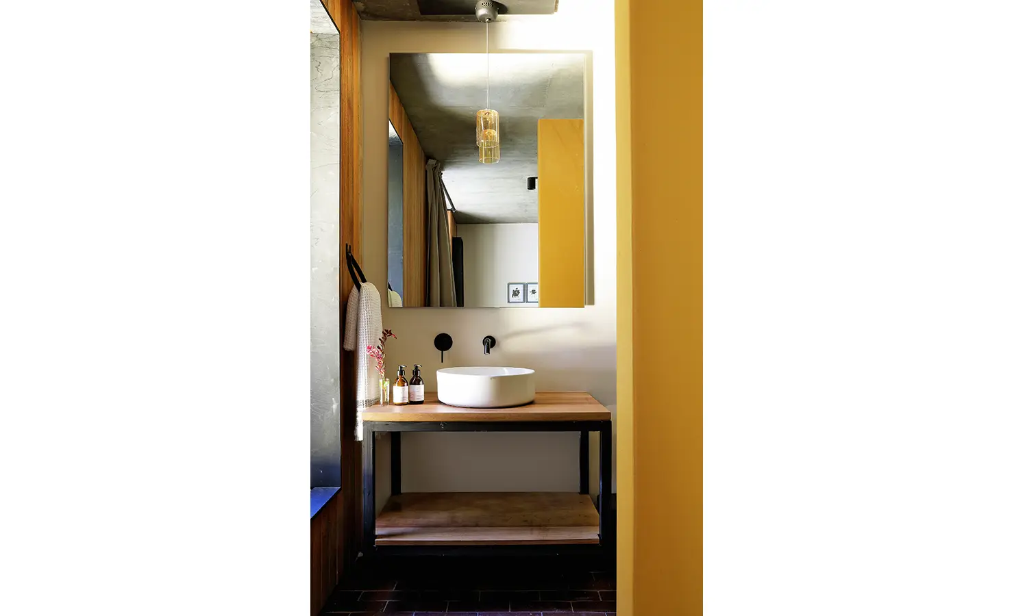 Perfect Hideaways: compact bathroom vanity with round vessel basin, black wall taps, amber pendant and warm yellow accents, Franschhoek, The Garden House