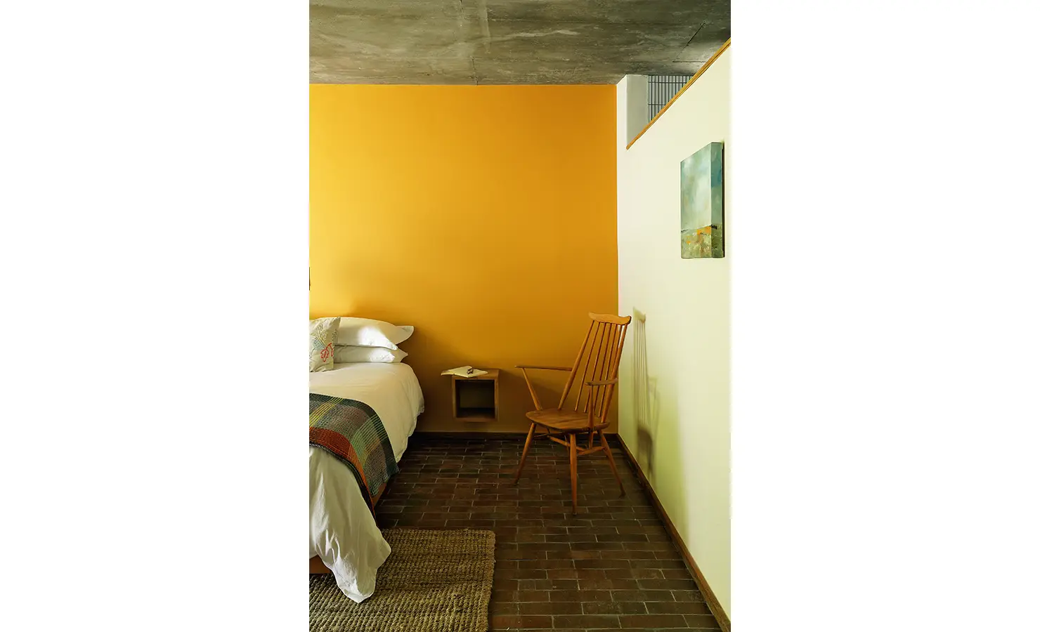 Perfect Hideaways: cosy bedroom corner with mustard feature wall, timber chair, floating bedside nook and patterned throw, Franschhoek, The Garden House