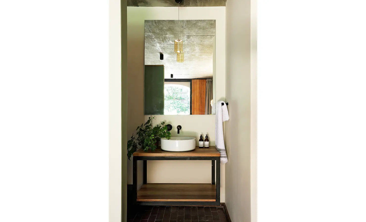 Perfect Hideaways: neat bathroom nook with round basin on a wood-and-steel vanity, amber pendant and black fittings, Franschhoek, The Garden House