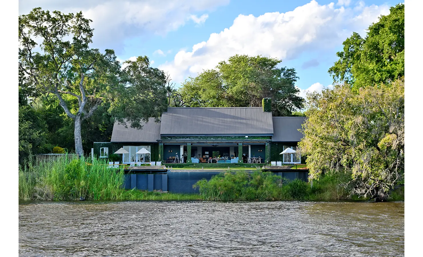Perfect Hideaways: Elegant riverside villa framed by lush greenery, with expansive open-plan living spaces overlooking the water, Tanyati Villa, Livingstone
