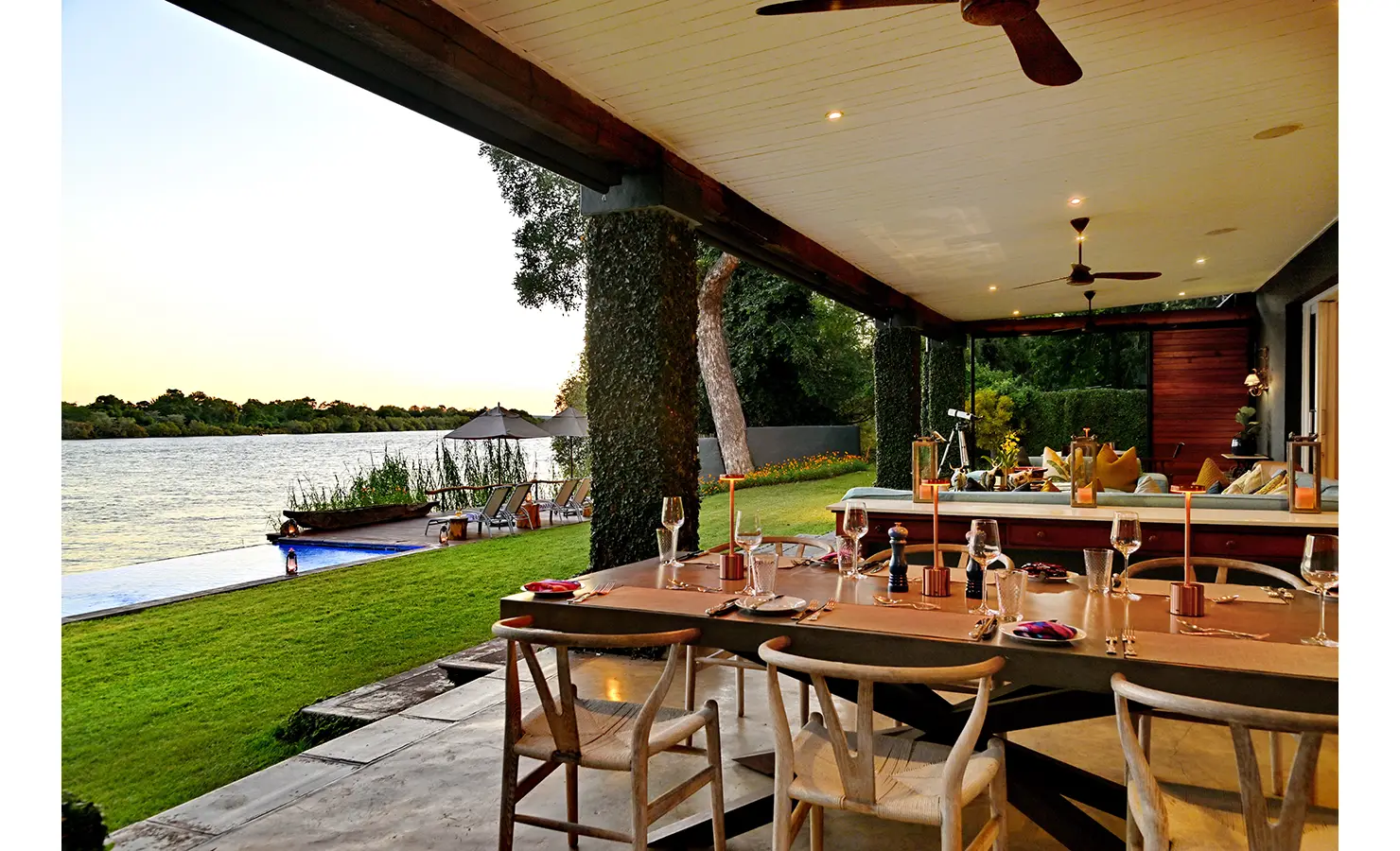 Perfect Hideaways: Covered outdoor dining and lounge area with sweeping river views and manicured lawns leading to the infinity pool, Tanyati Villa, Livingstone