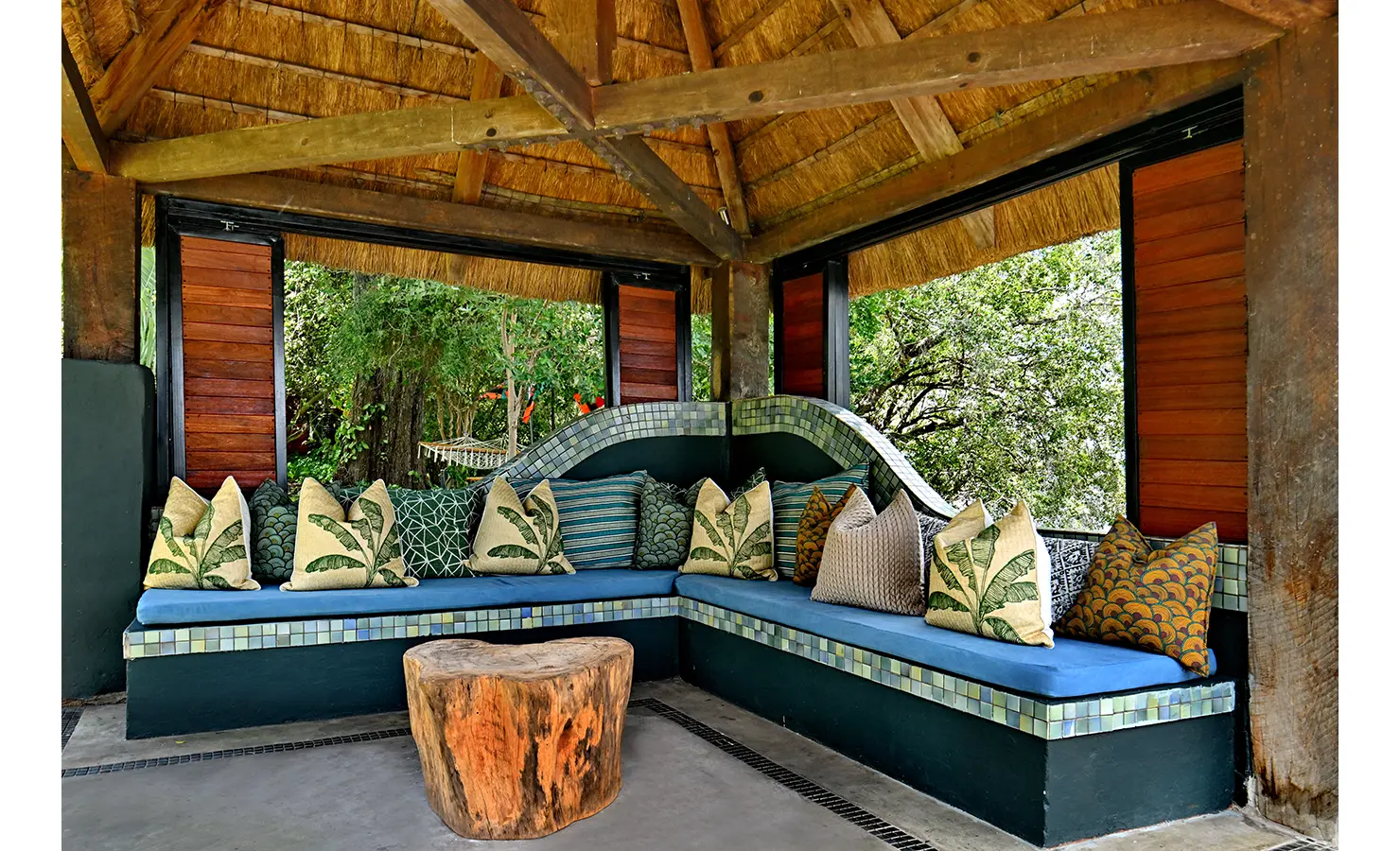 Perfect Hideaways: Thatched pavilion with built-in tiled seating, vibrant patterned cushions, and a rustic wooden table, Tanyati Villa, Livingstone