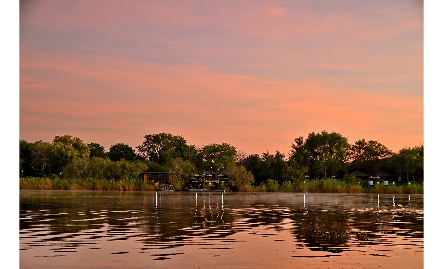 Perfect Hideaways: Riverbank view of the villa and jetty under a dramatic pink and orange sunset sky, Tanyati Villa, Livingstone