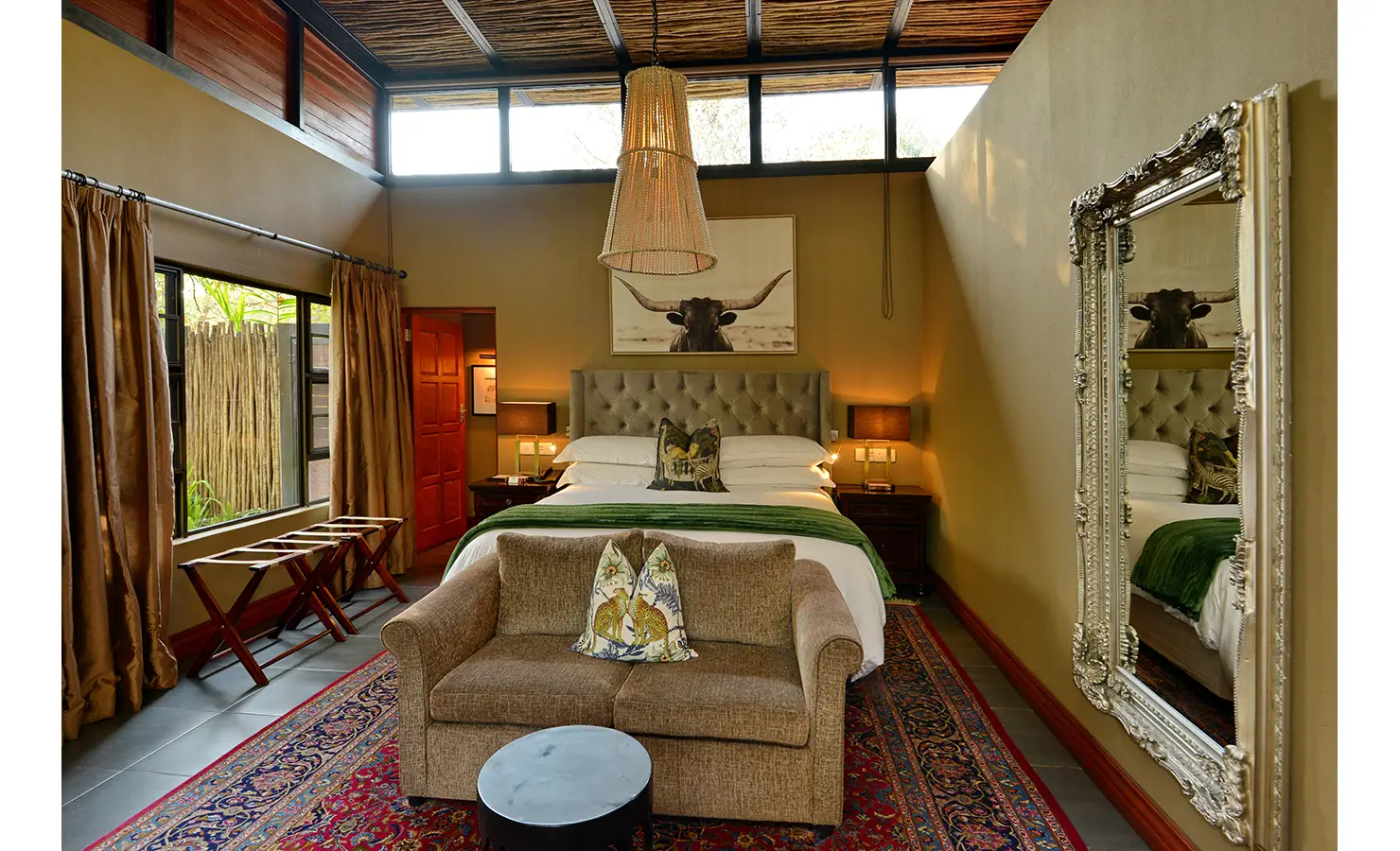Perfect Hideaways: serene bedroom with tufted headboard, beaded pendant light, sofa at the foot and a large ornate mirror — Mukwa River Lodge, Livingstone