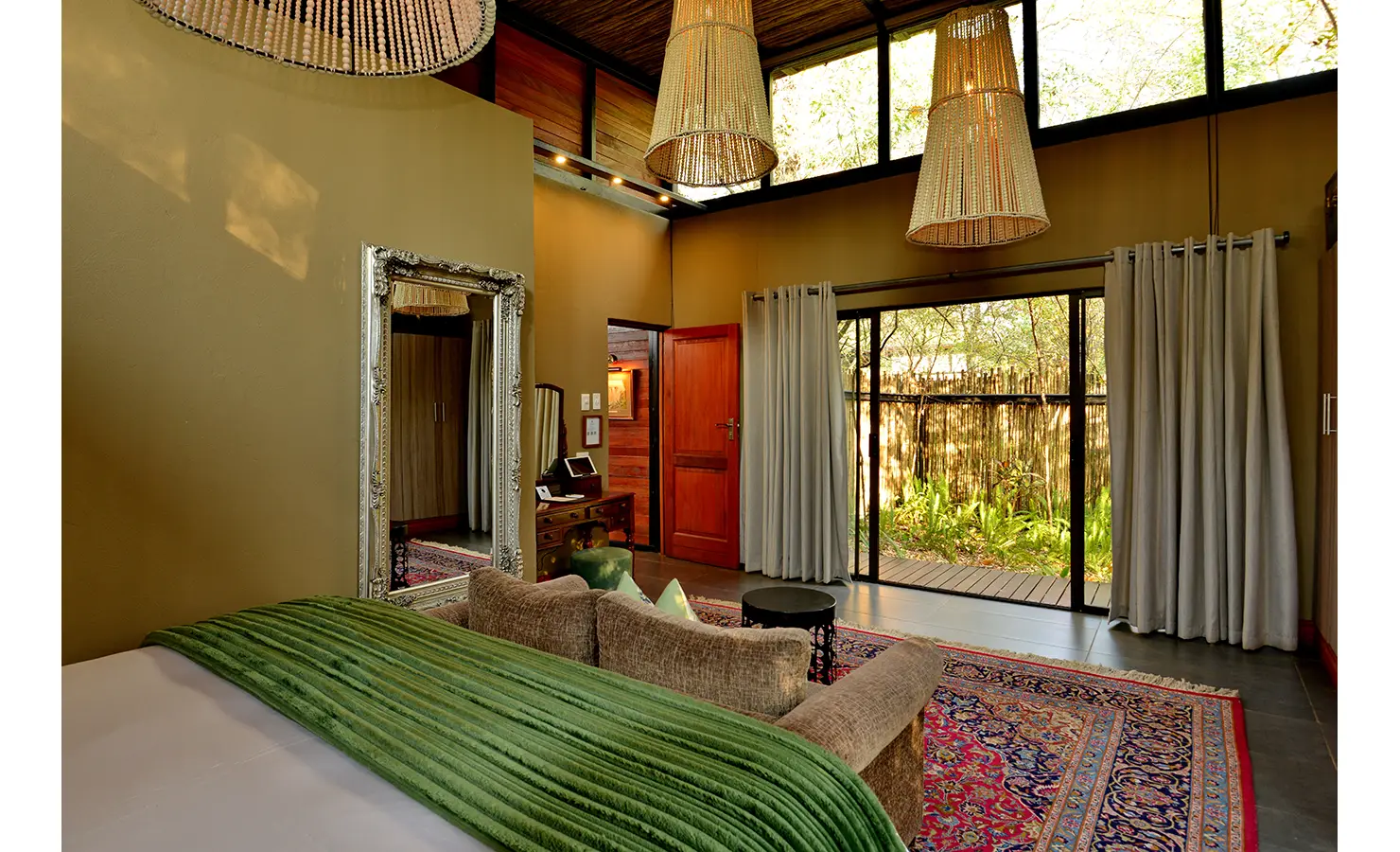 Perfect Hideaways: airy suite with clerestory windows, sliding doors to a private deck, oversized mirror and a soft green throw — Mukwa River Lodge, Livingstone