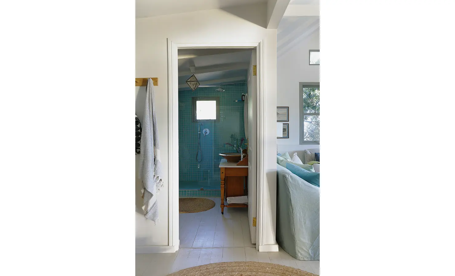 Perfect Hideaways: View through to a teal-tiled shower room with rain head and vintage vanity, jute rugs and soft light — fresh, beachy bathroom, Amongst The Trees, Scarborough.