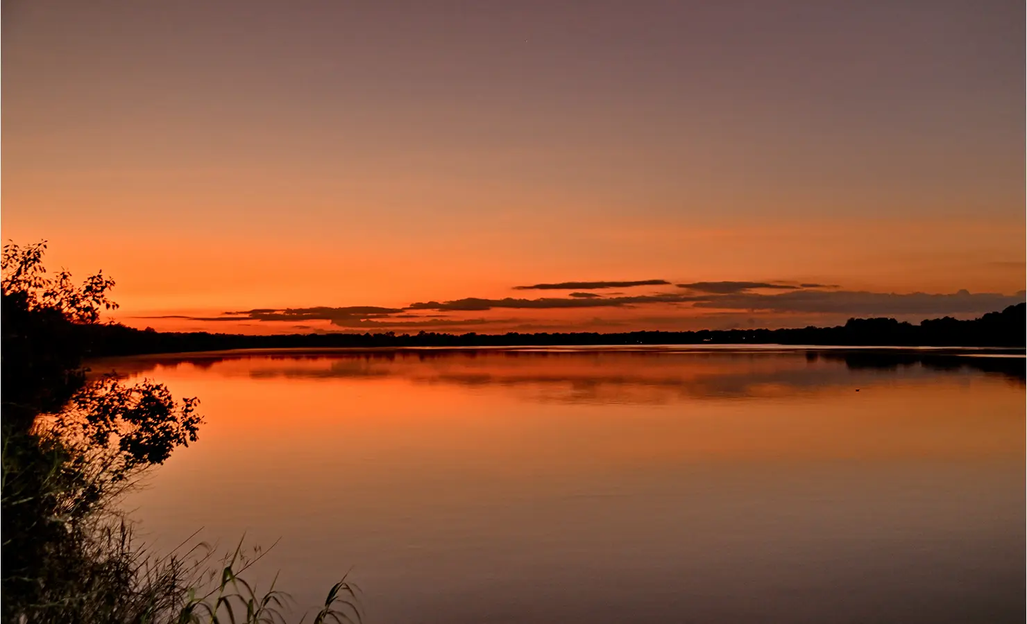 Perfect Hideaways: Peaceful Zambezi River at dusk reflecting the warm gradient of the sunset sky, framed by trees on the riverbank, Tanyati Villa, Livingstone