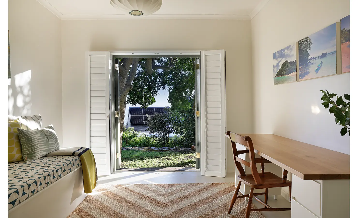 Perfect Hideaways: Garden room with long timber desk opposite a cushioned daybed; shutters open to lawn and trees — airy workspace, Amongst The Trees, Scarborough.
