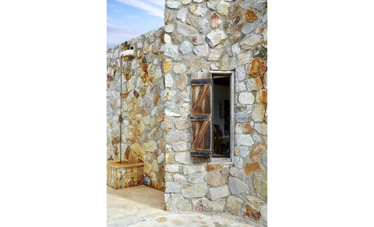 Perfect Hideaways: A close-up of the hideaway's stone façade with timber shutters and weathered patina, exuding a sense of timeless craftsmanship. Fynbos Fort, Plettenberg Bay.