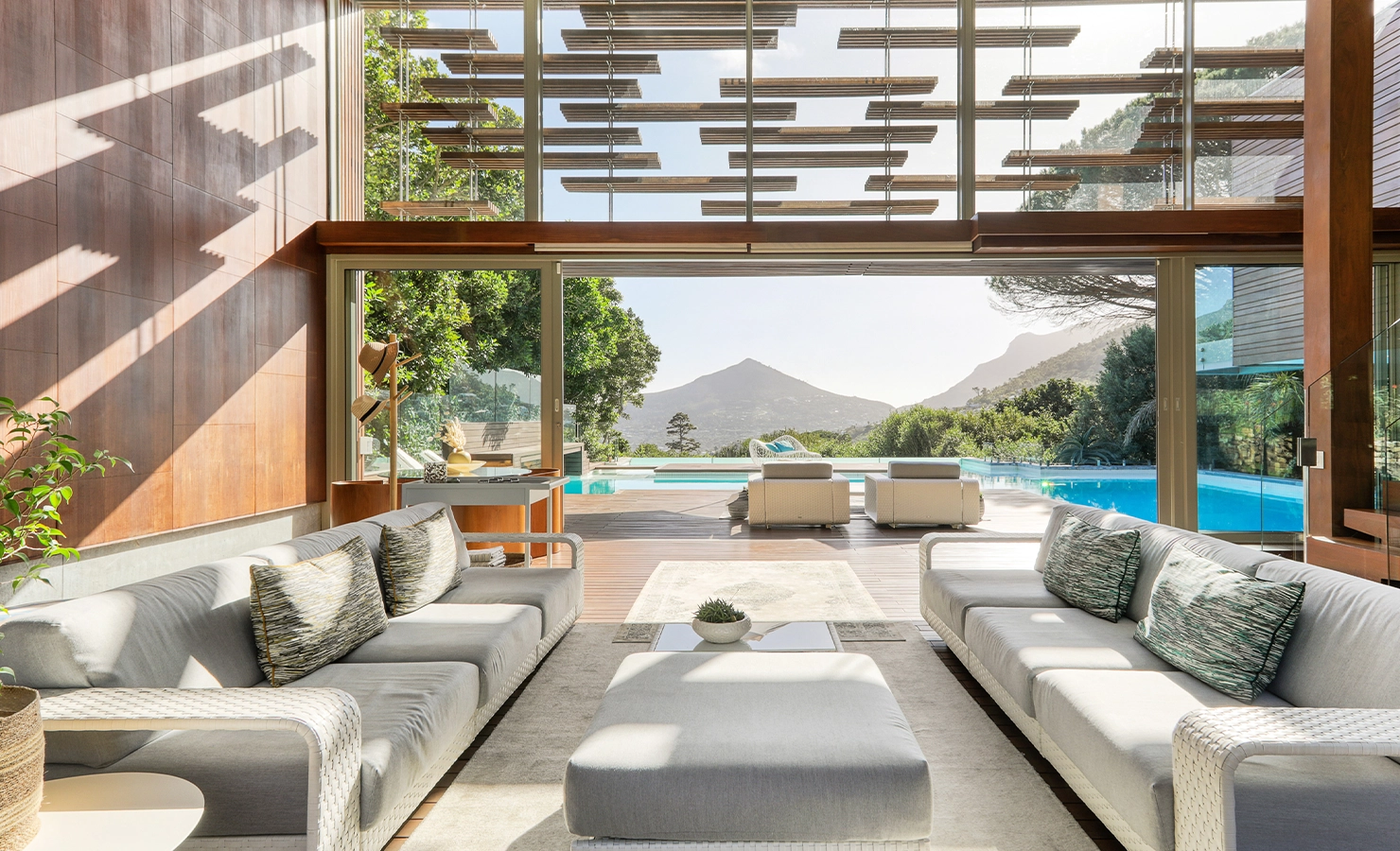 Perfect Hideaways: Double‑volume lounge with sliding glass opens onto the pool terrace, framed by timber louvres and mountain views, Spa House, Hout Bay