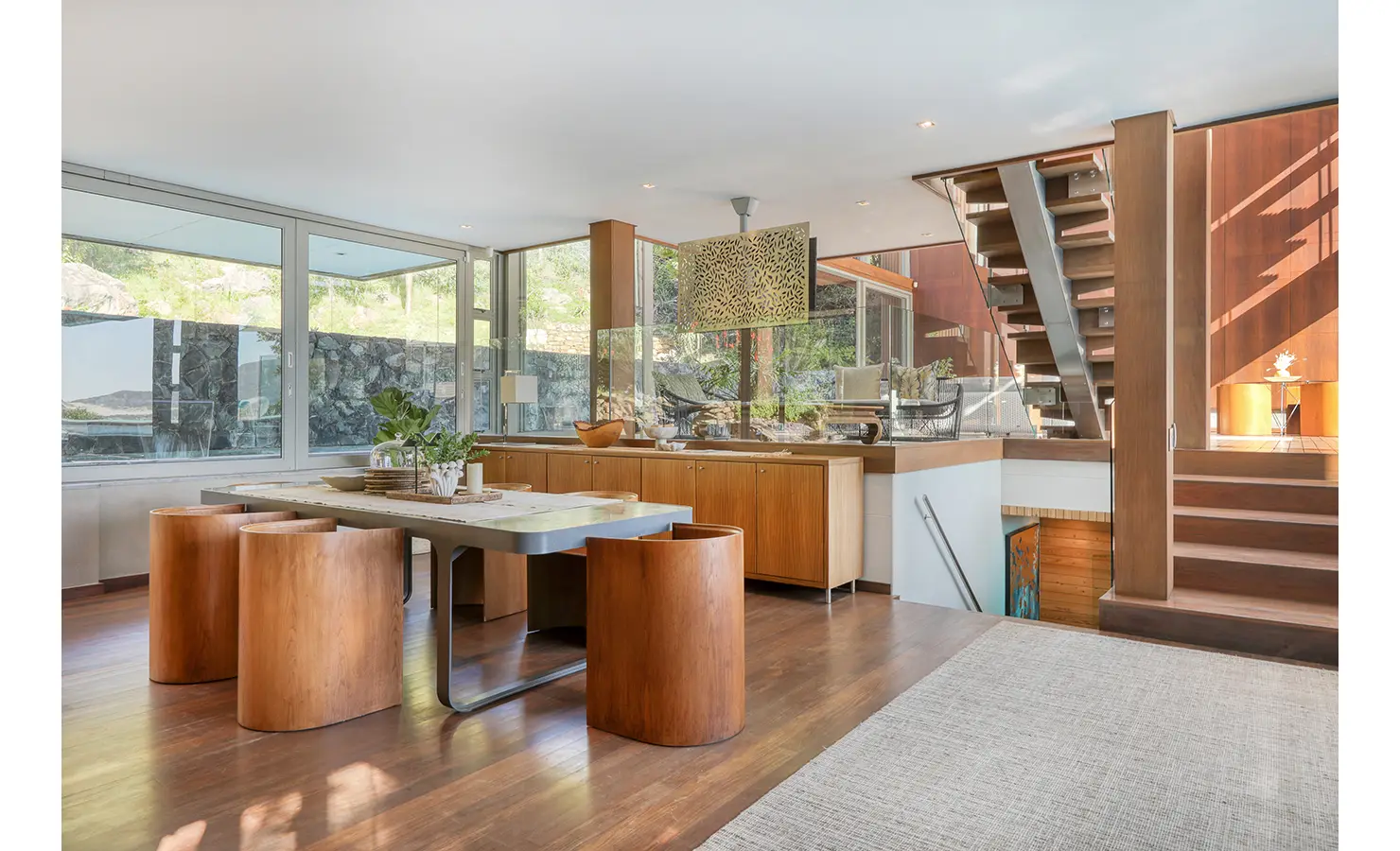 Perfect Hideaways: Warm timber interiors with bespoke dining table, sculptural stools and open staircase in a split‑level space, Spa House, Hout Bay