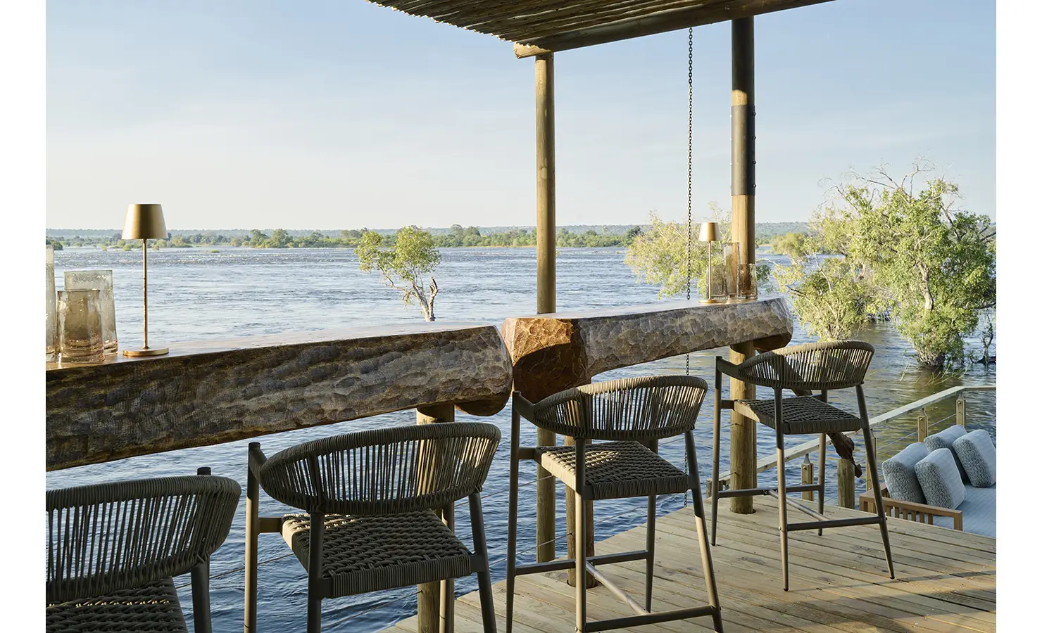 Perfect Hideaways: Elevated deck bar with carved timber counter and woven stools overlooking the Zambezi, Rapid's View Villa, Zambezi National Park