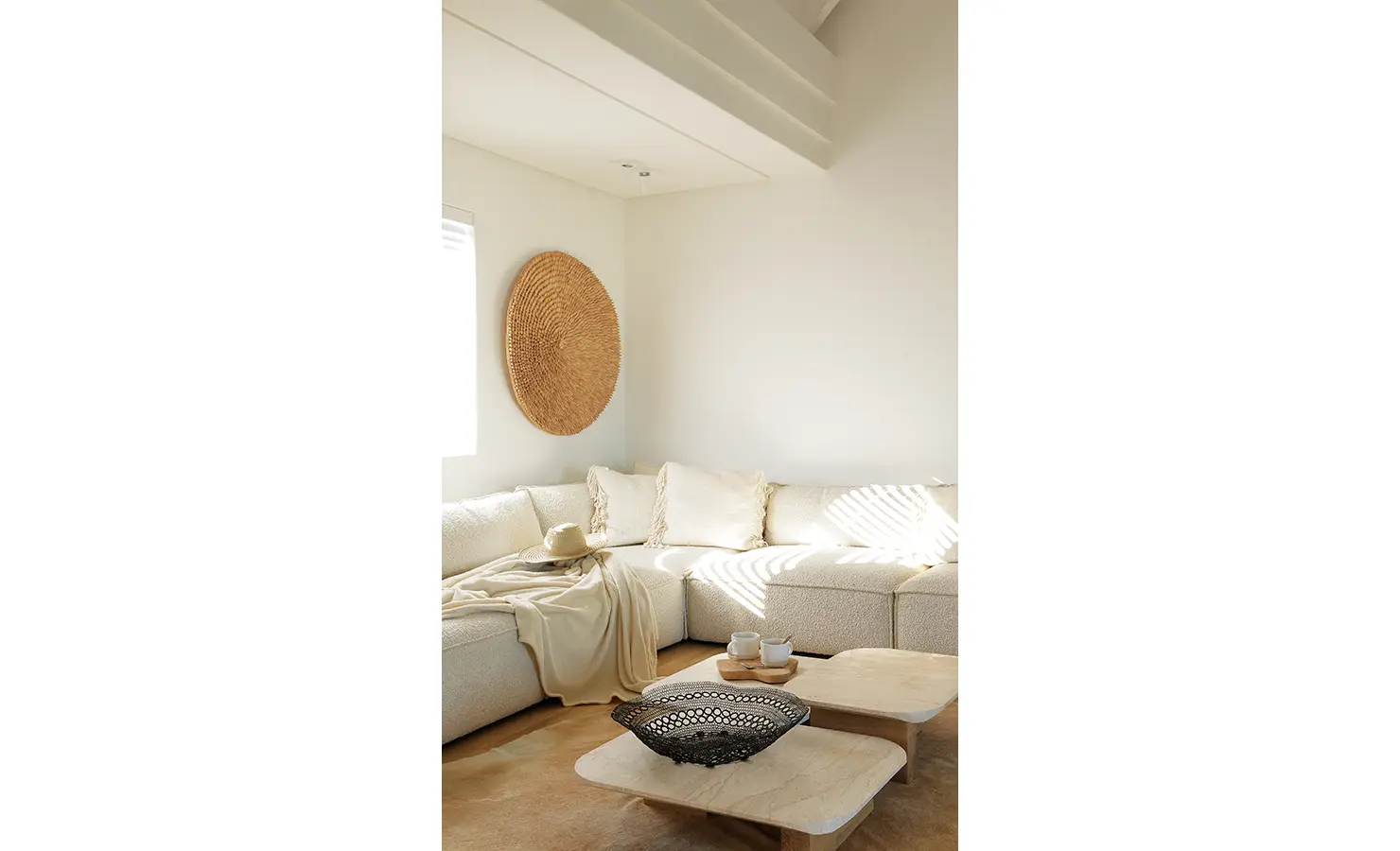 Perfect Hideaways: cosy corner lounge with cream sectional sofa, woven wall art and twin low stone tables catching soft afternoon light, Blanc de Blanc, Yzerfontein