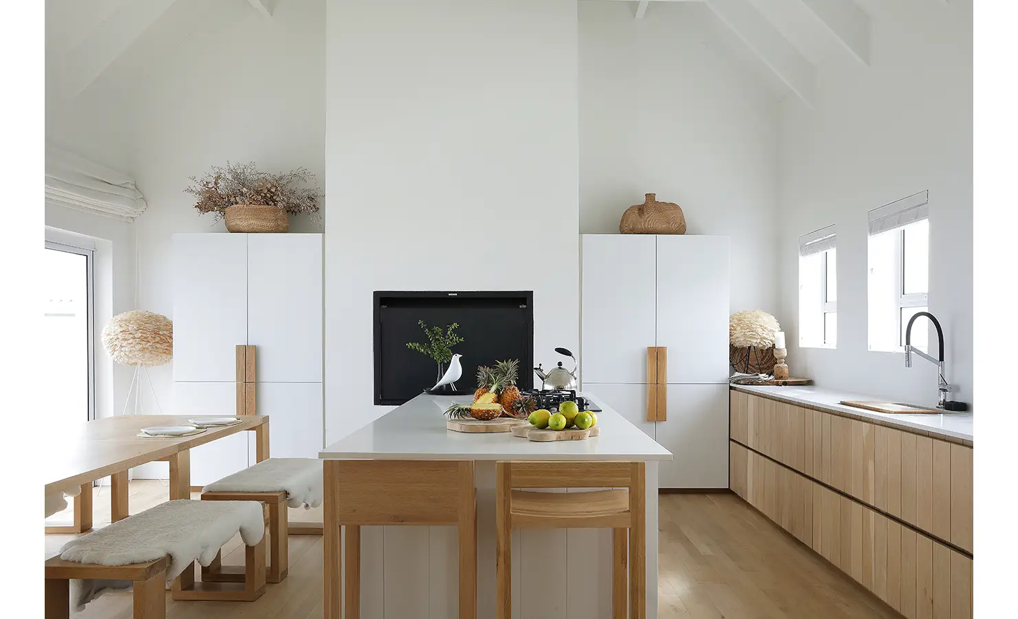 Perfect Hideaways: minimalist kitchen with pale timber cabinetry, white island and bench seating with sheepskin throws beneath a vaulted ceiling, Blanc de Blanc, Yzerfontein