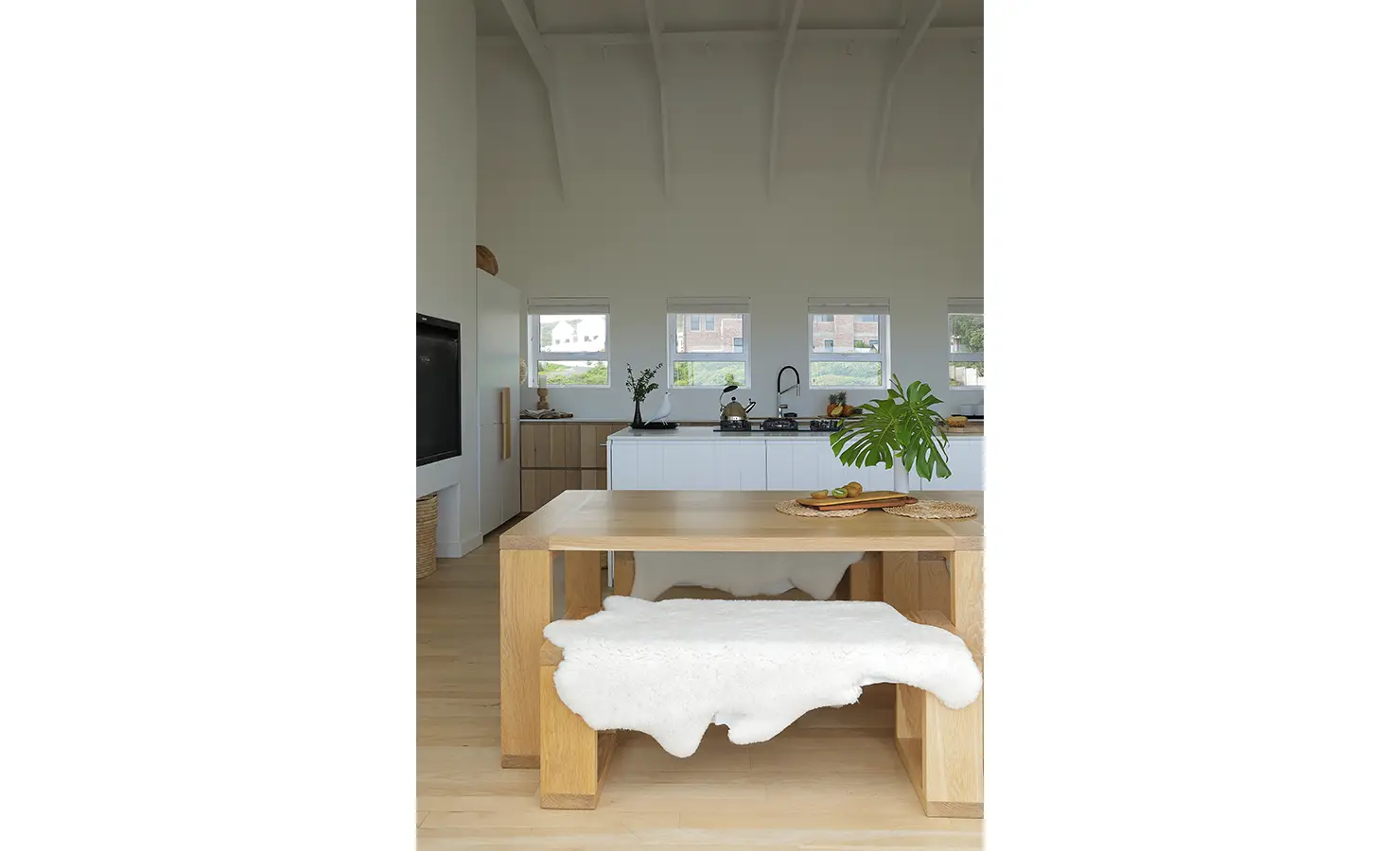 Perfect Hideaways: view across the dining table to a streamlined kitchen island and a row of small windows, bench seating draped with a soft hide, Blanc de Blanc, Yzerfontein