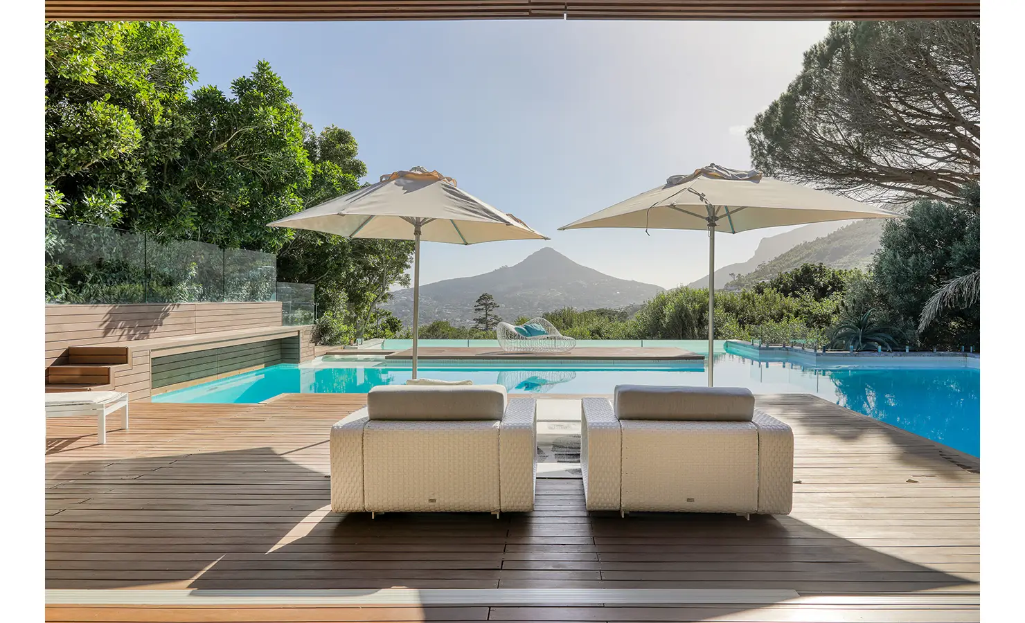 Perfect Hideaways: Terrace seating with twin parasols looking across the infinity pool to a valley and mountain panorama, Spa House, Hout Bay