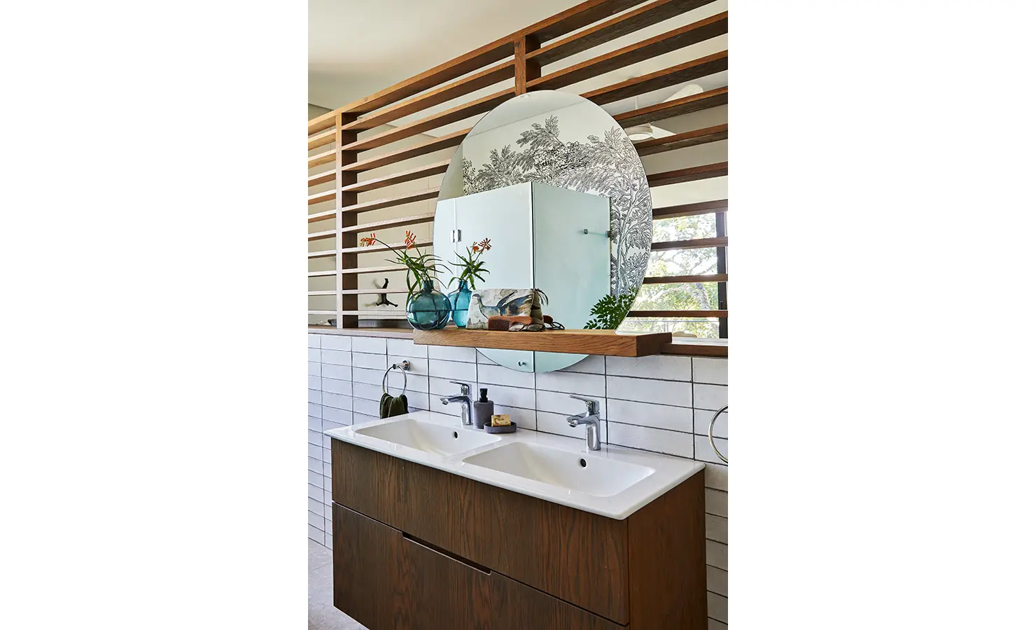 Perfect Hideaways: A contemporary bathroom vanity with double basins, a circular mirror, wood-panel detailing, and pops of greenery in glass vases. St Austel, Kenton-on-Sea