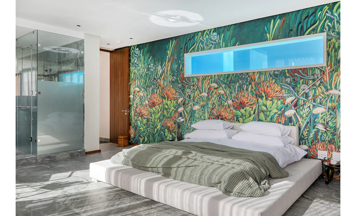 Perfect Hideaways: Protea-inspired mural bedroom with low platform bed, blue recessed shelf and adjoining frosted-glass shower, Spa House, Hout Bay