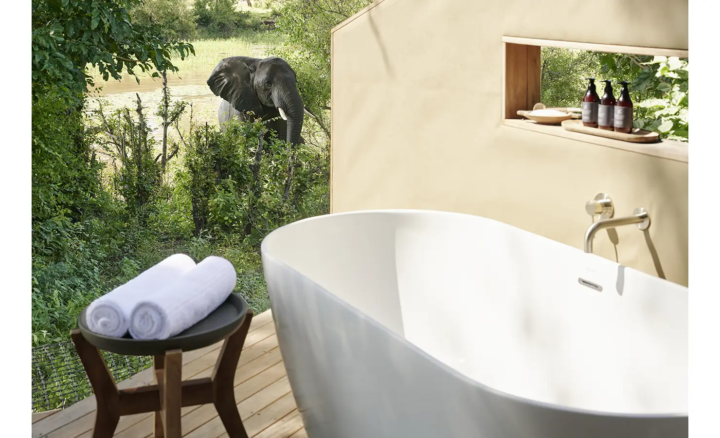 Perfect Hideaways: Freestanding bathtub on a timber deck with views into the bush, where elephants roam nearby. Hippo Creek Villa, Zambezi National Park.