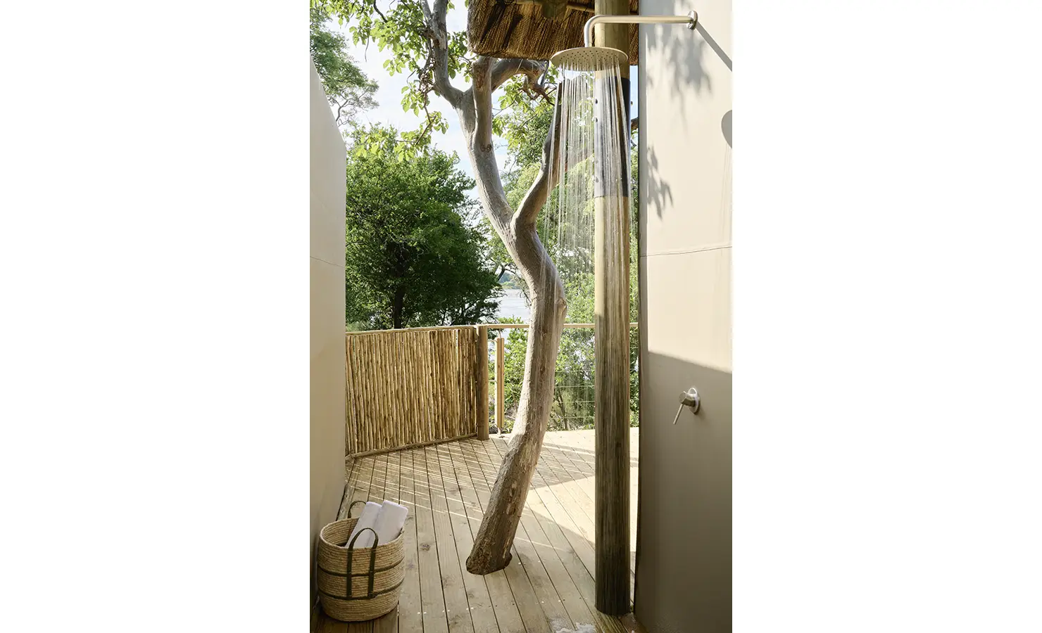 Perfect Hideaways: Outdoor shower alcove where a tree rises through the timber decking with river glimpses beyond, Rapid's View Villa, Zambezi National Park