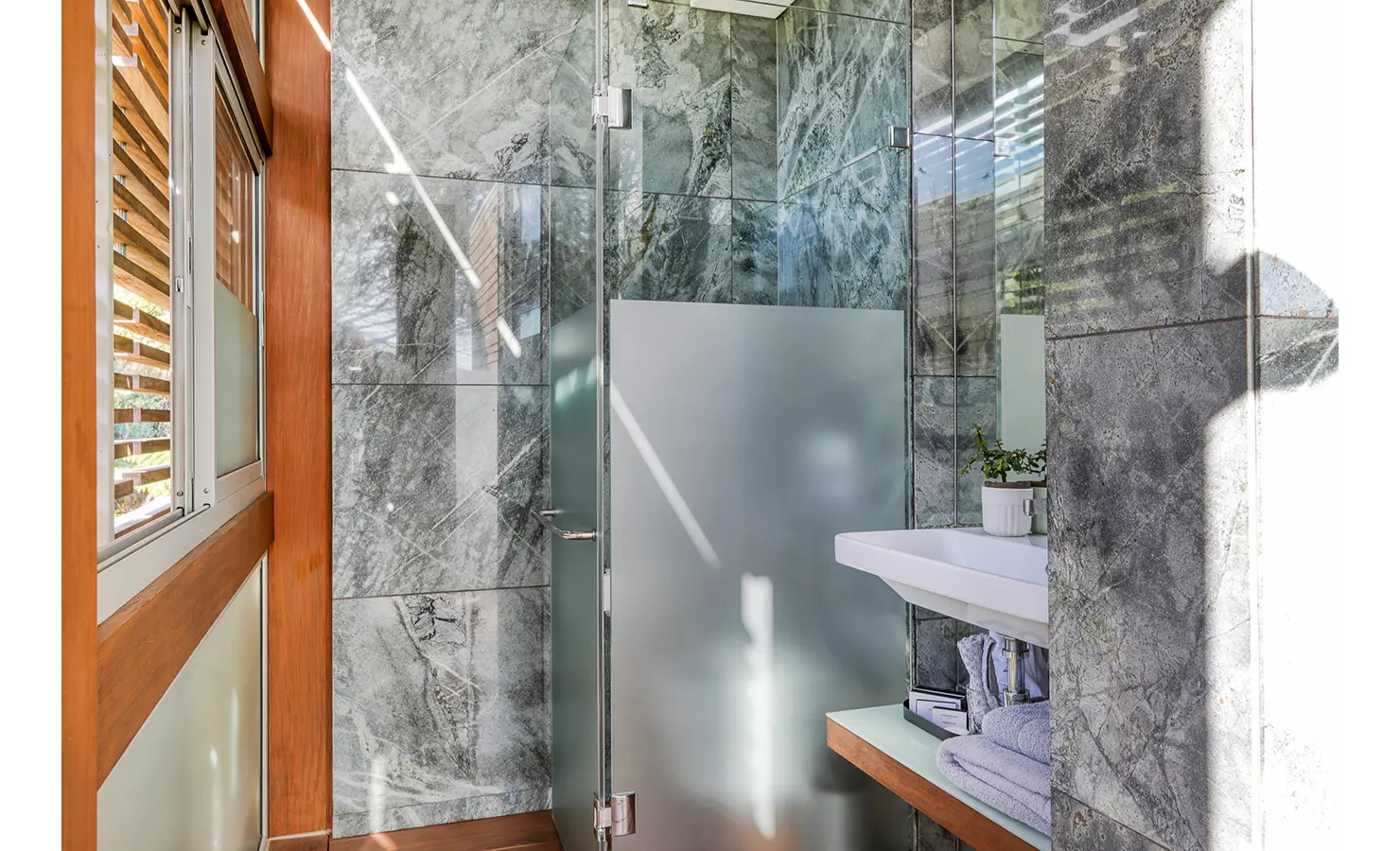 Perfect Hideaways: Compact bathroom lined in grey marble with frosted-glass shower, floating basin and louvred window, Spa House, Hout Bay