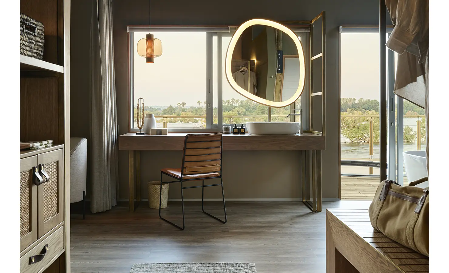 Perfect Hideaways: Dressing table with sculptural illuminated mirror and picture-window views across the river, Rapid's View Villa, Zambezi National Park