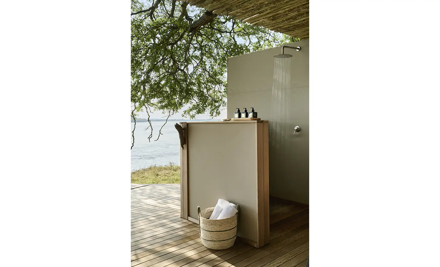 Perfect Hideaways: Outdoor shower on a timber deck shaded by branches, overlooking the Zambezi. Hippo Creek Villa, Zambezi National Park.