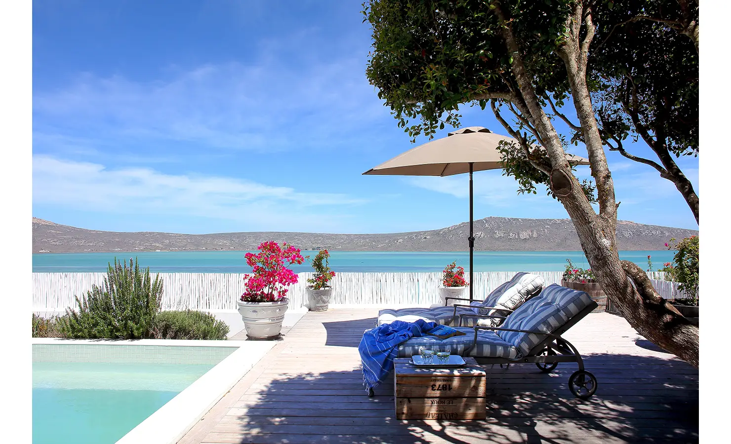 Perfect Hideaways: poolside deck with striped sun loungers under a parasol, pots of bougainvillea and sweeping turquoise lagoon views, Langebaan, Lagoon Lookout.