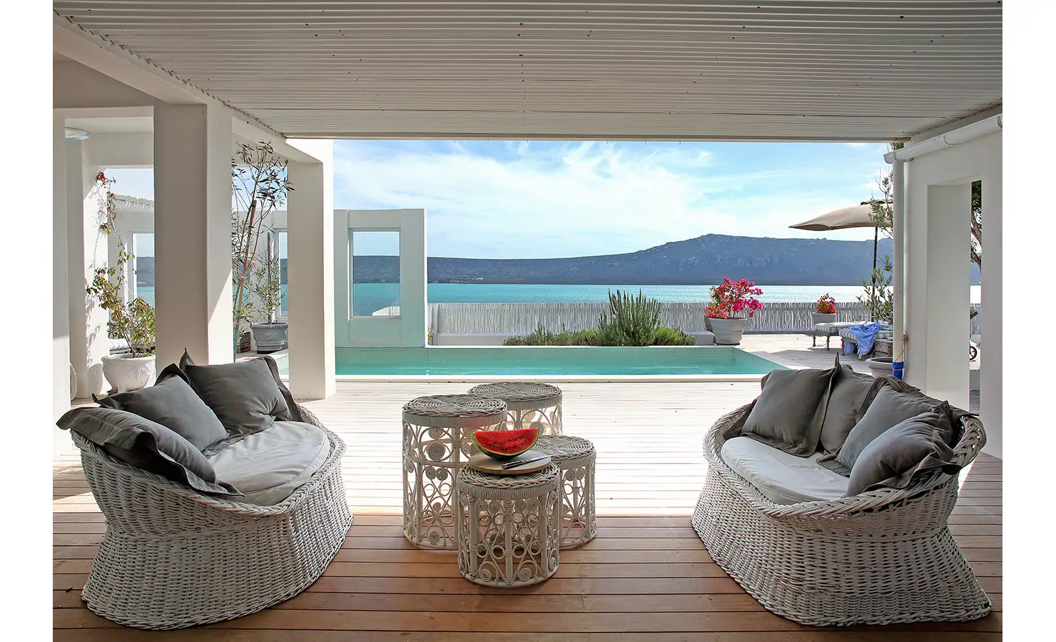 Perfect Hideaways: covered deck with curved wicker sofas and ornate side tables overlooking the pool and glittering lagoon, Langebaan, Lagoon Lookout.