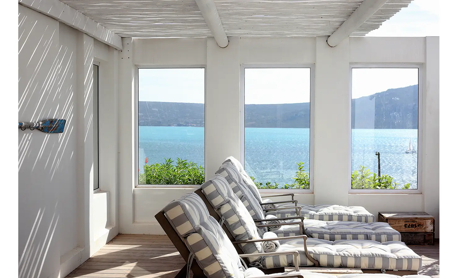 Perfect Hideaways: glass-framed sun lounge with rows of padded striped recliners facing the lagoon, Langebaan, Lagoon Lookout.