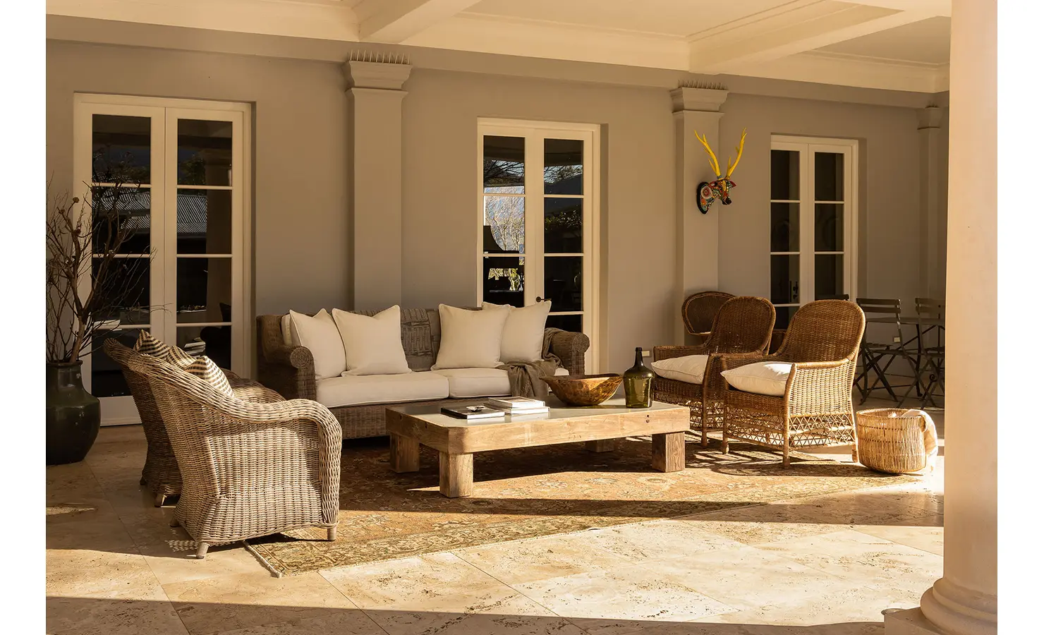 Perfect Hideaways sunlit covered patio with wicker armchairs, white cushions, and a wooden coffee table creating a cozy outdoor living space, Franschhoek, Varuna.