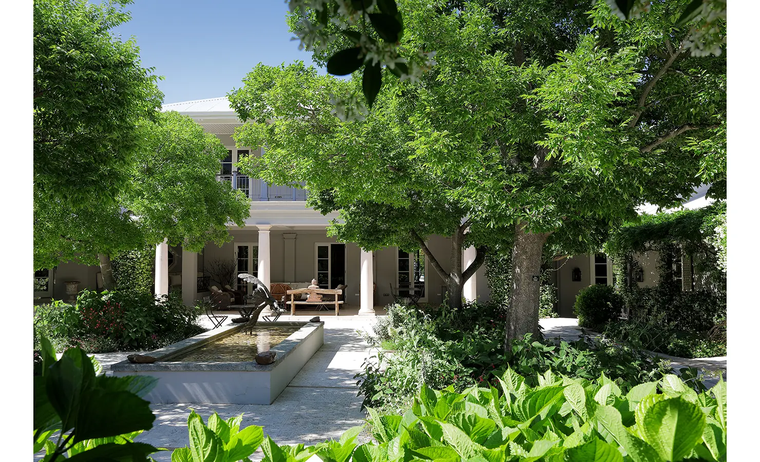 Perfect Hideaways tranquil courtyard with lush green trees, shaded seating areas, and a long water feature leading to the veranda, Franschhoek, Varuna.