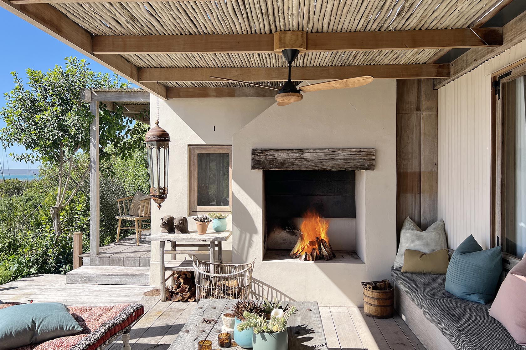 Perfect Hideaways- Covered outdoor seating area with a built-in fireplace, wooden beams overhead, cushioned benches, rustic furniture and a lit fire creating a cosy atmosphere overlooking coastal greenery, Yellowwood Cottage, Churchhaven, Western Cape, South Africa