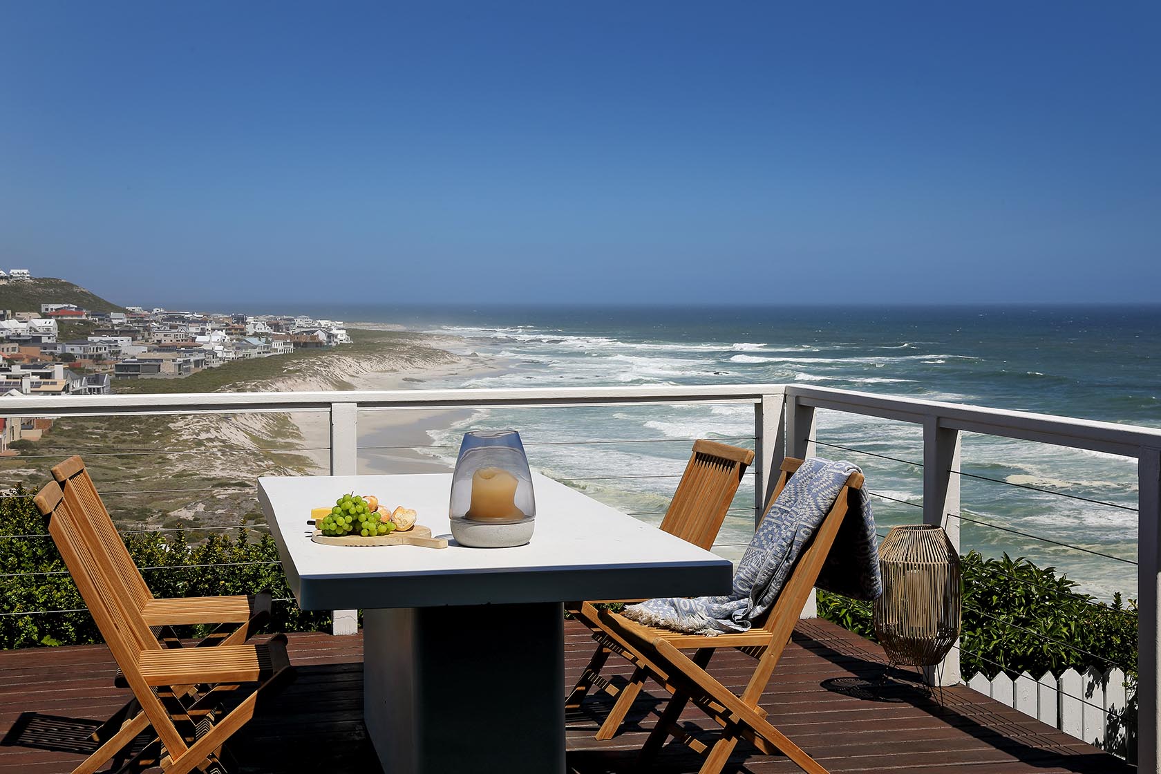 Perfect Hideaways - Ocean-facing deck with a white outdoor table and wooden chairs, set above rolling waves and sandy shoreline with sweeping views across Yzerfontein Cape Cottage_Yzerfontein_West Coast_Western Cape_South Africa